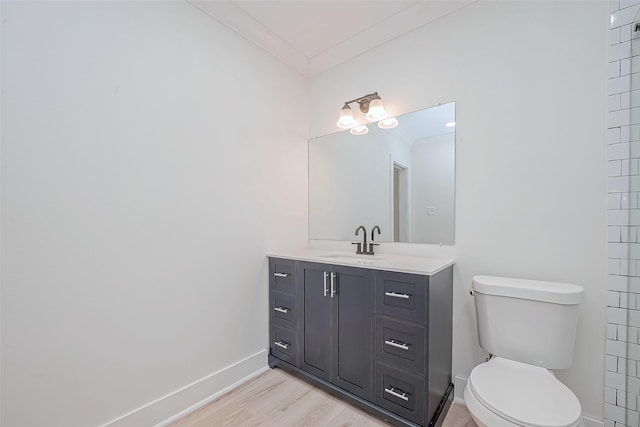 bathroom with crown molding, baseboards, toilet, vanity, and wood finished floors
