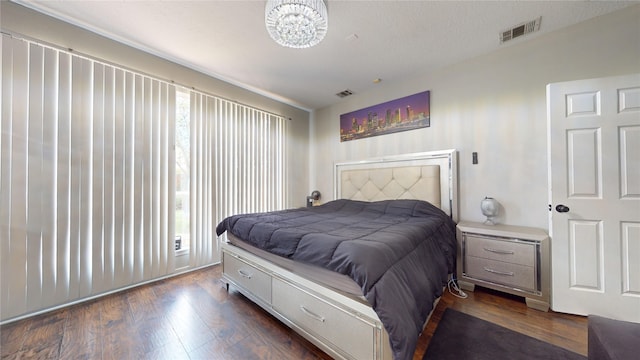 bedroom featuring dark hardwood / wood-style flooring, a textured ceiling, and an inviting chandelier