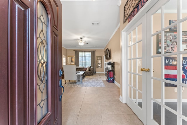 entrance foyer with ceiling fan, light tile patterned floors, crown molding, and french doors