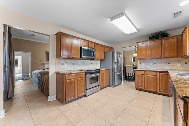 kitchen featuring tasteful backsplash, light stone counters, appliances with stainless steel finishes, light tile patterned floors, and ornamental molding