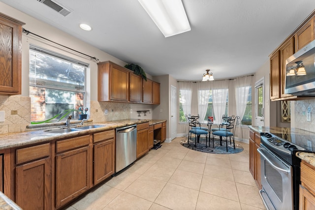 kitchen featuring decorative backsplash, light tile patterned floors, sink, and appliances with stainless steel finishes