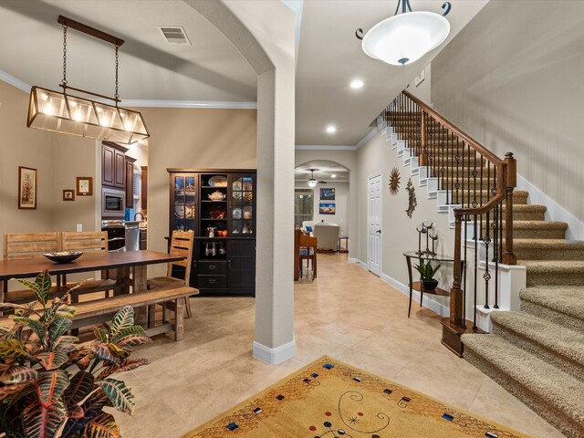 foyer entrance featuring light tile patterned floors and crown molding