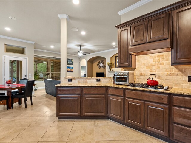 kitchen with ornamental molding, decorative backsplash, ceiling fan, and light stone countertops