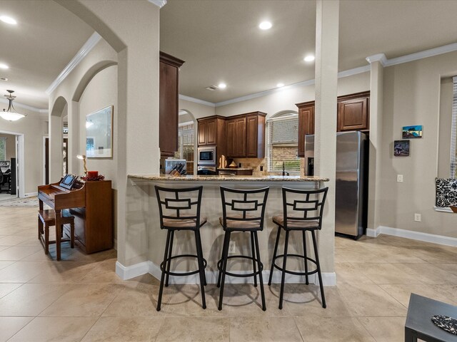 kitchen featuring appliances with stainless steel finishes, light stone countertops, crown molding, and kitchen peninsula