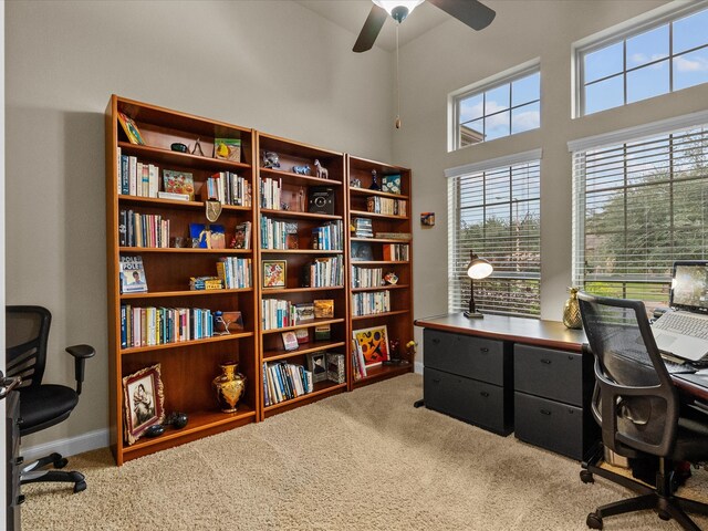 carpeted home office featuring a towering ceiling and ceiling fan