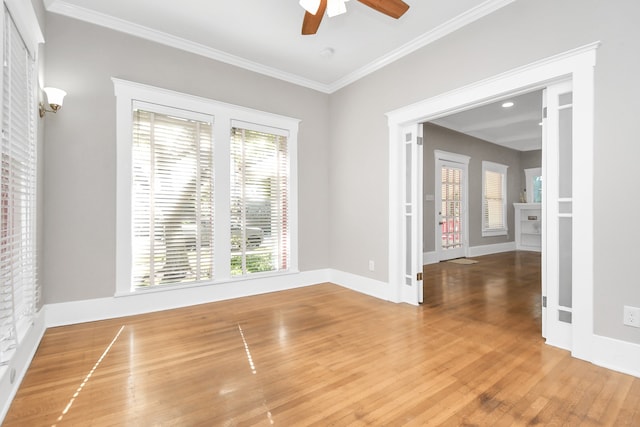 spare room with a fireplace, hardwood / wood-style floors, ceiling fan, and crown molding