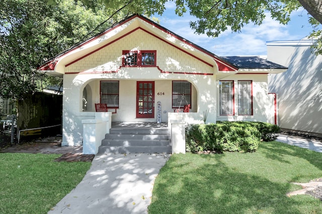 bungalow with a porch and a front lawn