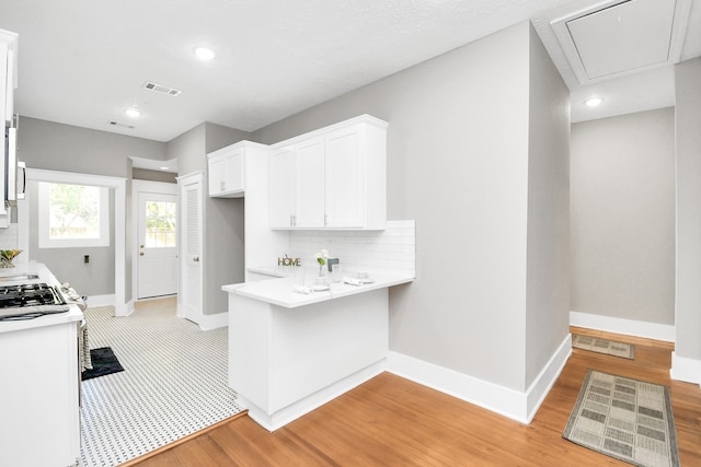 kitchen featuring light wood-type flooring, decorative backsplash, white range, and white cabinetry