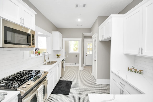 kitchen featuring white cabinets, backsplash, stainless steel appliances, and sink