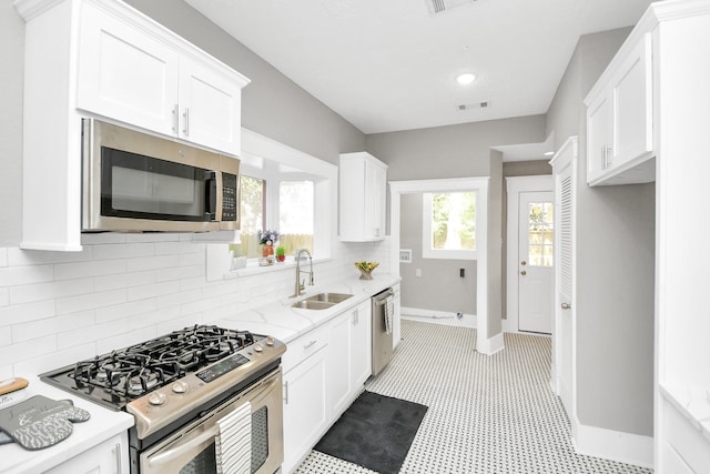 kitchen with light stone countertops, white cabinetry, sink, and appliances with stainless steel finishes