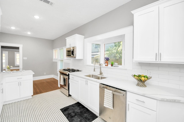 kitchen with sink, white cabinetry, stainless steel appliances, and tasteful backsplash