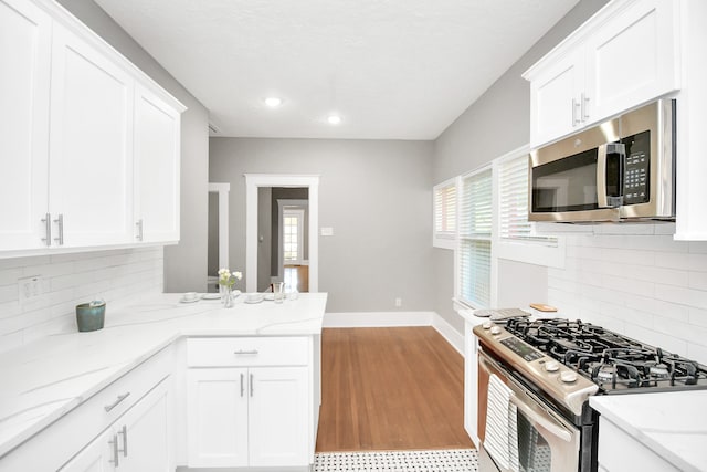 kitchen with white cabinets, light stone countertops, and stainless steel appliances