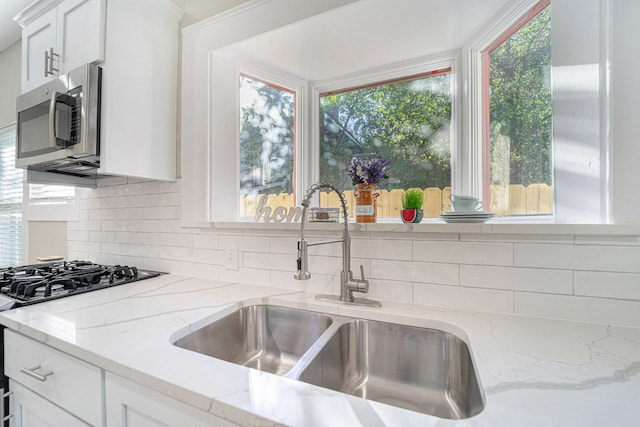 kitchen with sink, white cabinets, a healthy amount of sunlight, and stove