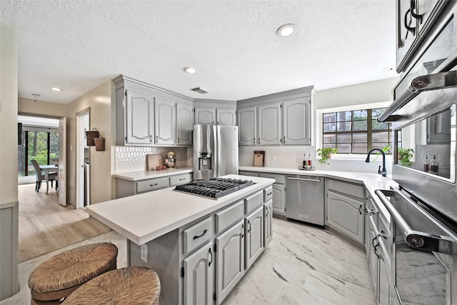 kitchen with a kitchen island, tasteful backsplash, a healthy amount of sunlight, and stainless steel appliances