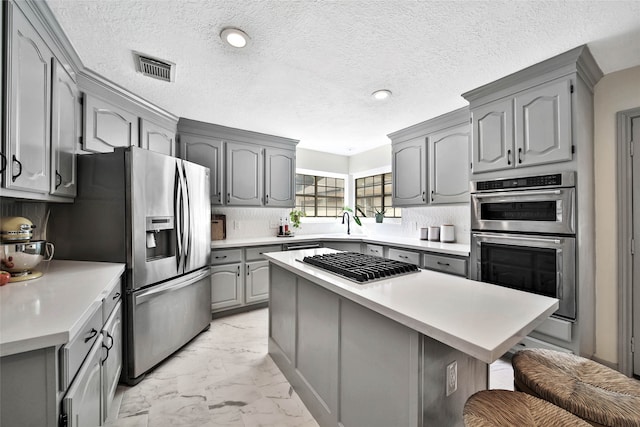 kitchen featuring stainless steel appliances, tasteful backsplash, a kitchen breakfast bar, gray cabinets, and a kitchen island