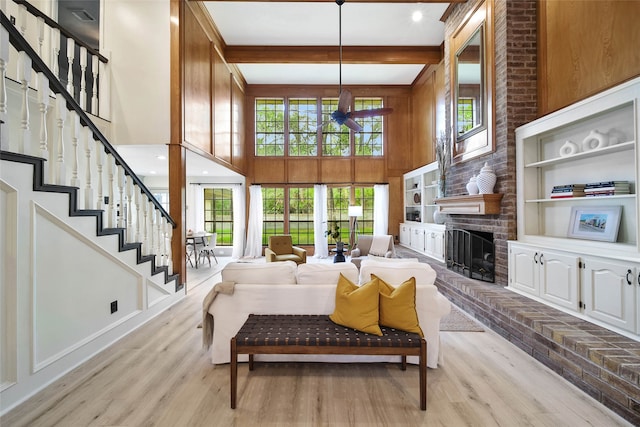 living room with light wood-type flooring, a towering ceiling, a healthy amount of sunlight, and beam ceiling