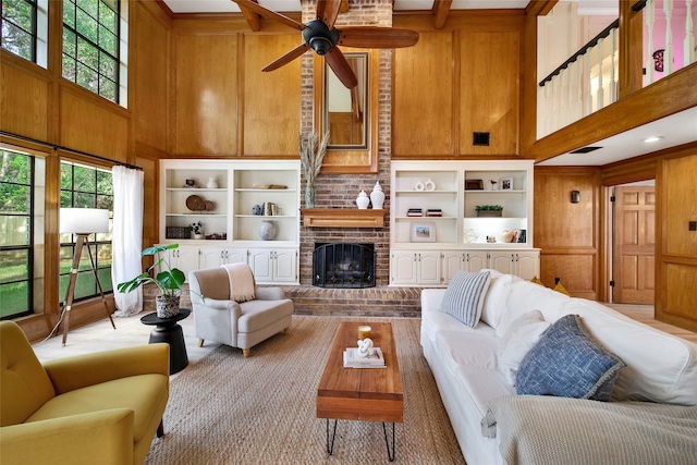 living room featuring a fireplace, a towering ceiling, ceiling fan, and wooden walls