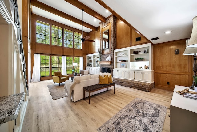 living room featuring wood walls, a wealth of natural light, a fireplace, and light wood-type flooring