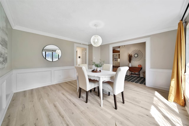 dining area featuring ornamental molding, light hardwood / wood-style floors, and an inviting chandelier