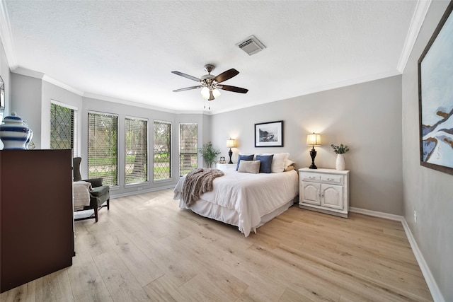 bedroom featuring a textured ceiling, light wood-type flooring, ceiling fan, and crown molding