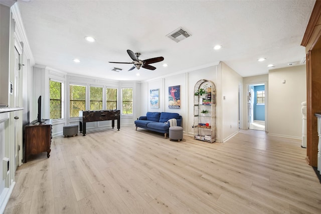 living room featuring ornamental molding, light hardwood / wood-style flooring, a textured ceiling, and ceiling fan