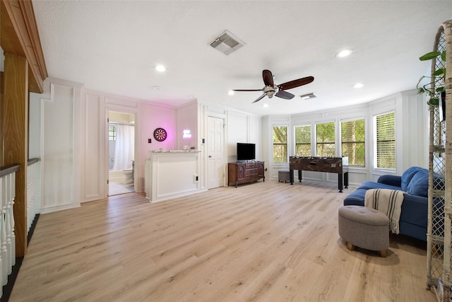 living room with light hardwood / wood-style floors, ceiling fan, and crown molding