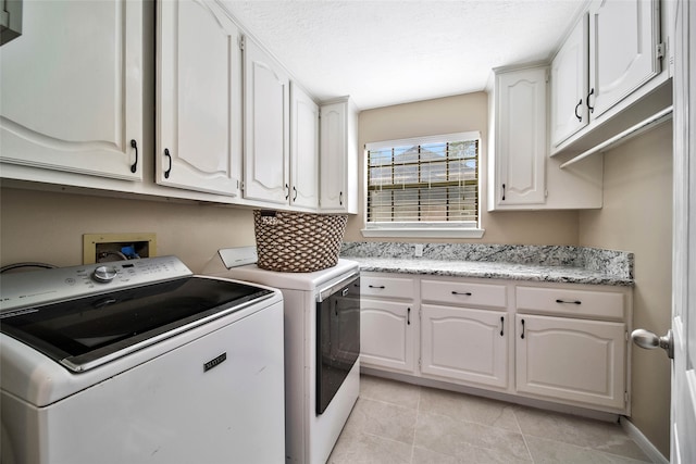 laundry area featuring washer and clothes dryer, cabinets, and light tile patterned flooring