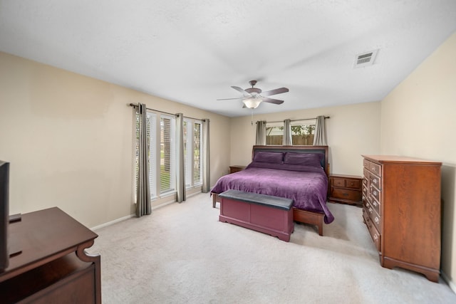 bedroom with multiple windows, ceiling fan, and light carpet