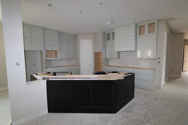 kitchen featuring white cabinetry, a spacious island, and light carpet