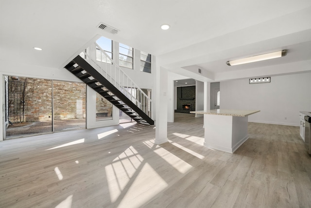 unfurnished living room featuring a brick fireplace and light hardwood / wood-style flooring