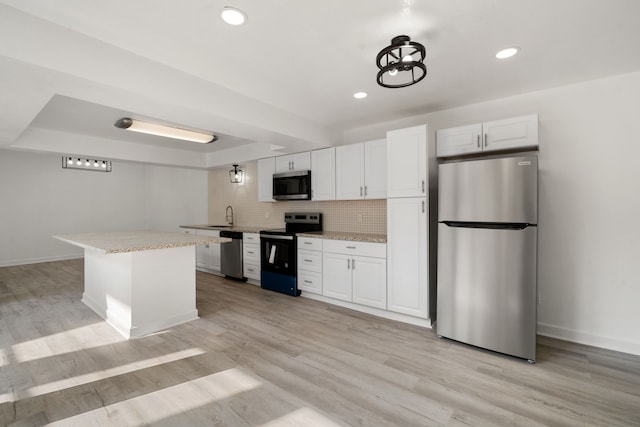 kitchen with white cabinetry, stainless steel appliances, light hardwood / wood-style floors, and a center island