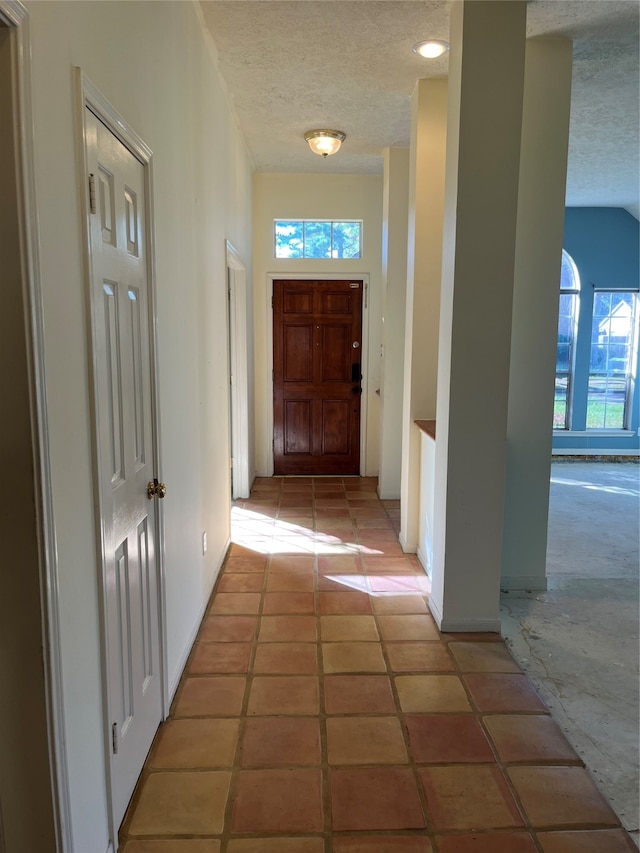 hall featuring a textured ceiling and light tile patterned floors