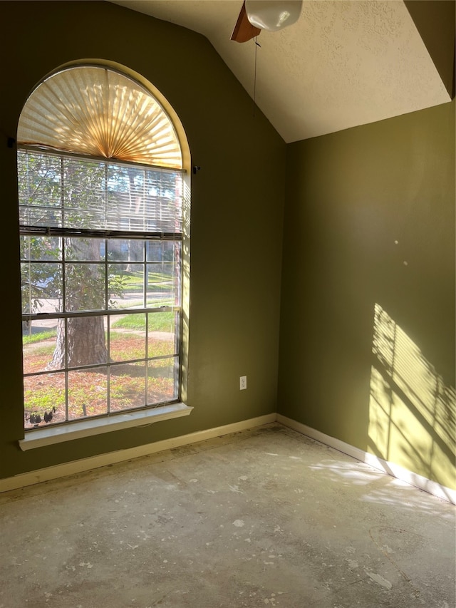 empty room featuring concrete flooring, lofted ceiling, and a textured ceiling