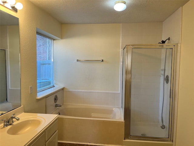 bathroom with plus walk in shower, vanity, and a textured ceiling