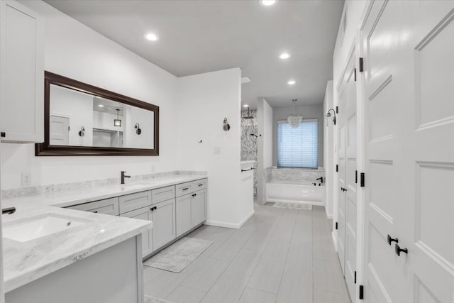 bathroom featuring plus walk in shower, vanity, and an inviting chandelier