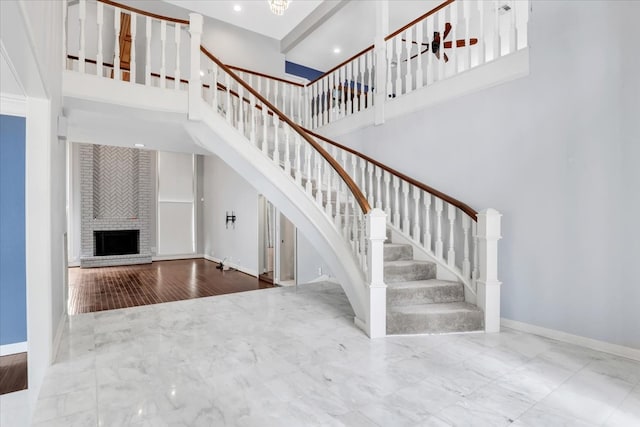 staircase featuring a towering ceiling, a fireplace, and hardwood / wood-style floors