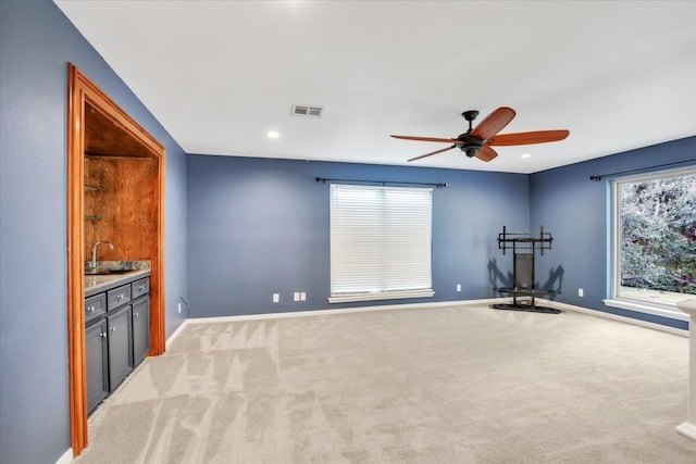 exercise room featuring light carpet, ceiling fan, and sink