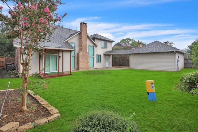 back of property with central air condition unit and a yard