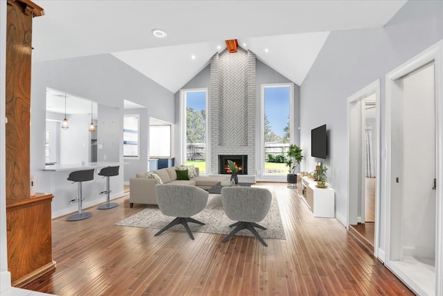 living room with a fireplace, hardwood / wood-style flooring, beam ceiling, and high vaulted ceiling