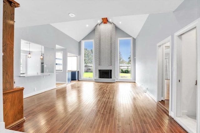 unfurnished living room with hardwood / wood-style floors, a fireplace, high vaulted ceiling, and beam ceiling