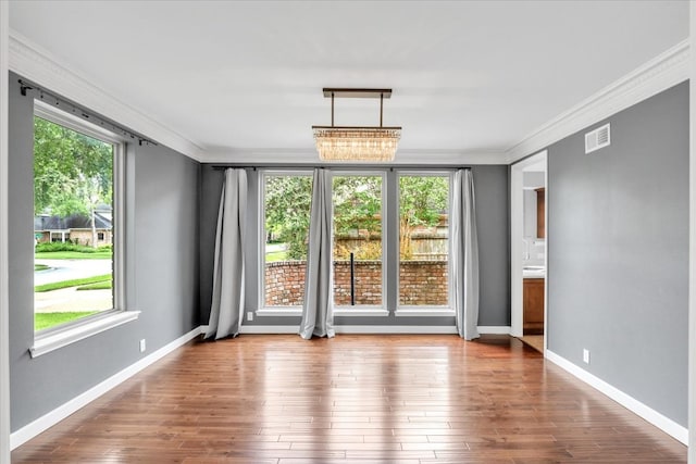 empty room featuring dark wood-type flooring, a notable chandelier, and ornamental molding