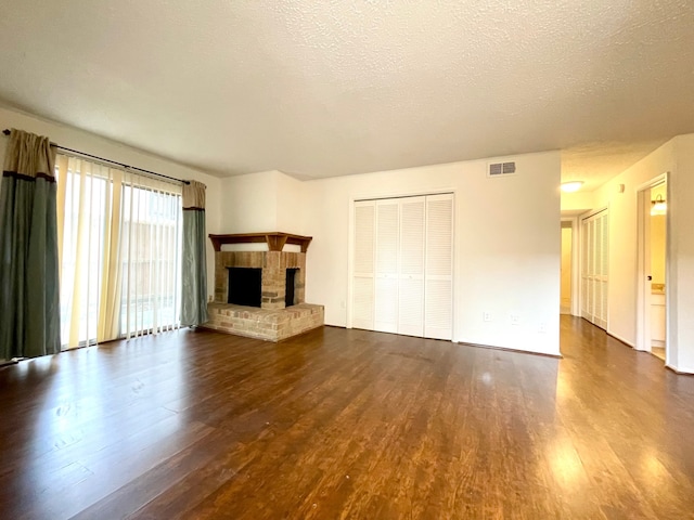 unfurnished living room with a textured ceiling, a fireplace, and dark hardwood / wood-style floors