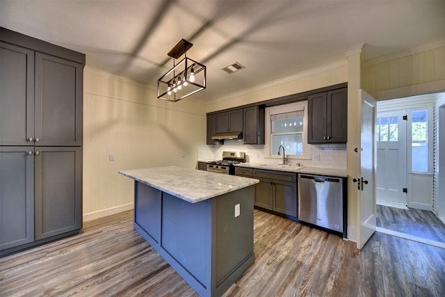 kitchen featuring wood-type flooring, crown molding, a kitchen island, appliances with stainless steel finishes, and pendant lighting