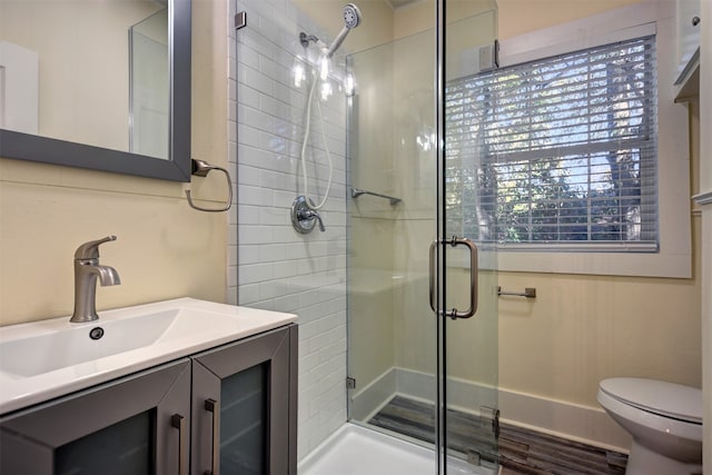 bathroom with a shower with door, vanity, and toilet