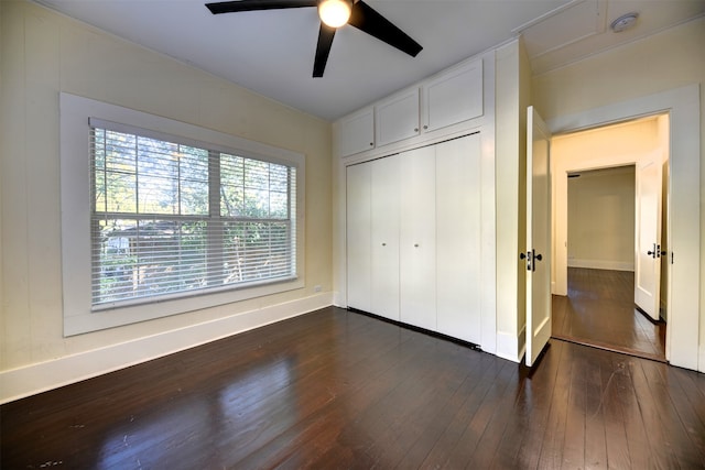 unfurnished bedroom featuring dark wood-type flooring, a closet, multiple windows, and ceiling fan