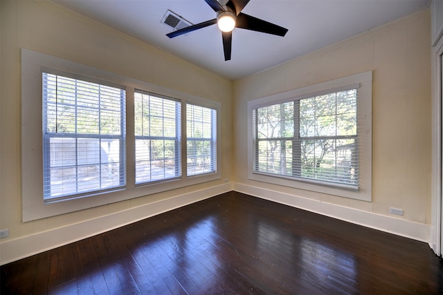 empty room with ceiling fan, a wealth of natural light, and dark hardwood / wood-style floors