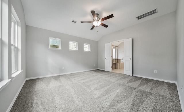 unfurnished bedroom with carpet flooring, ceiling fan, ensuite bathroom, and vaulted ceiling