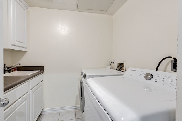 laundry area with washer and clothes dryer, cabinets, sink, and light tile patterned floors