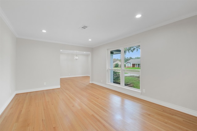 spare room with ornamental molding, a notable chandelier, and light wood-type flooring