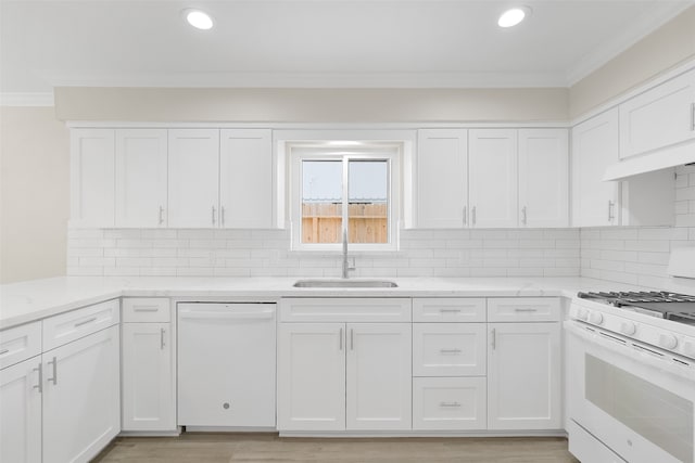 kitchen with ornamental molding, white appliances, sink, light hardwood / wood-style floors, and white cabinetry